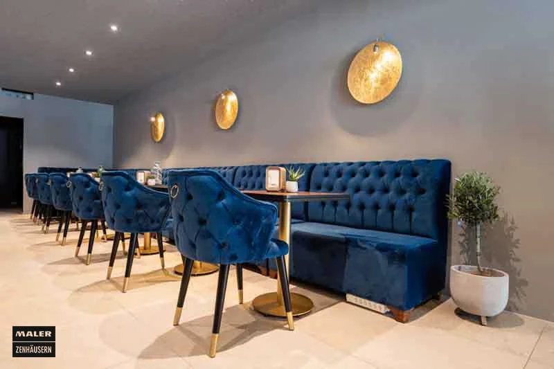 Sitzecke mit blauen Sitzpolstern und goldenen Details der Luna Cafe Bar