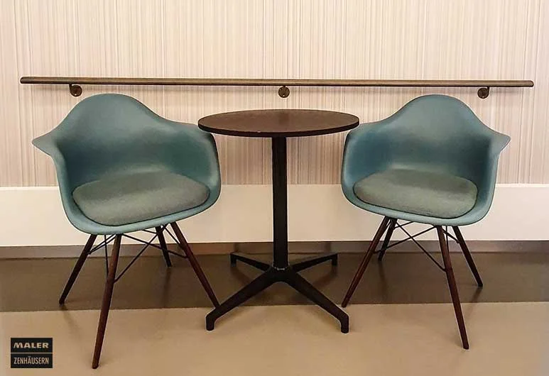 Zwei mintfarbene Vitra Stühle mit Tisch in der Mitte und Vescom Wandbekleidung