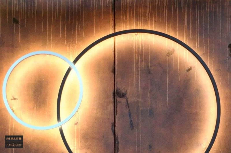 Foto einer Wand, die mit Rostoptik aufgewertet wurde. An der Wand hängen zwei runde, moderne Leuchten