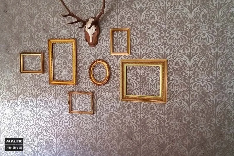 Foto einer kreativen Wandtapete mit Muster und leeren, goldenen Bilderrahmen